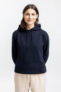 Das Frauen Model trägt den Rotholz Logo Hoodie aus Bio-Baumwolle in Schwarz