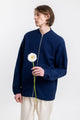 Das Männer Model trägt die leichte Rotholz Bomberjacke aus Bio-Baumwolle in Blau